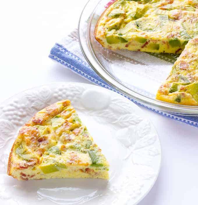 Avocado Bacon Crustless Quiche with one piece taken out and put on a white plate