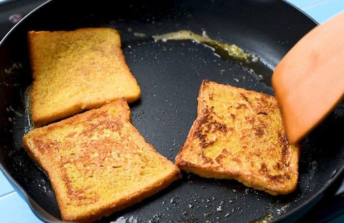 flipping over fluffy french toast in a hot skillet with butter