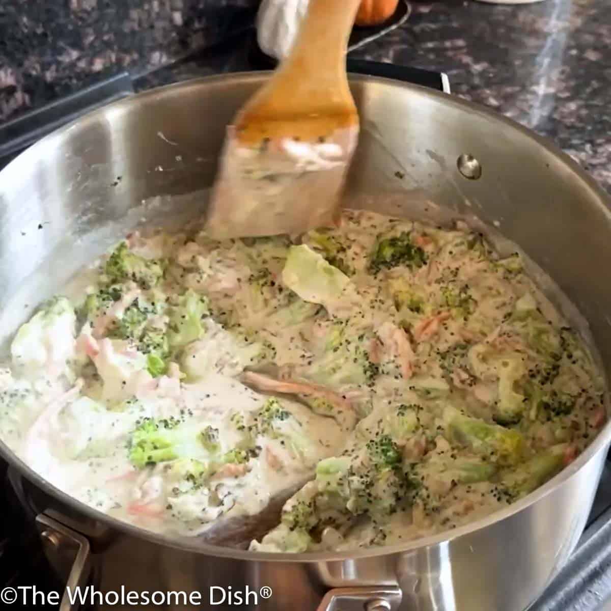 Stirring half and half into the soup pot full of vegetables.