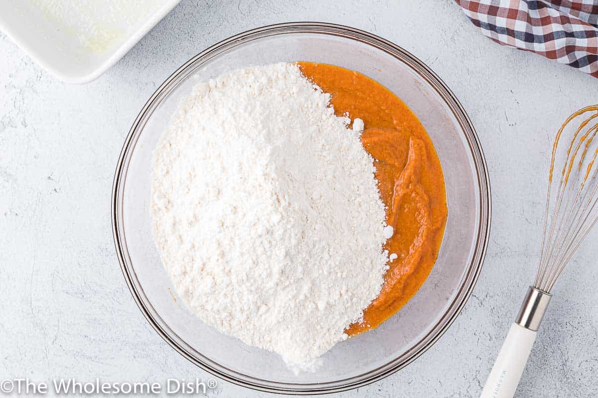 Adding yellow cake mix to a bowl with pumpkin puree.