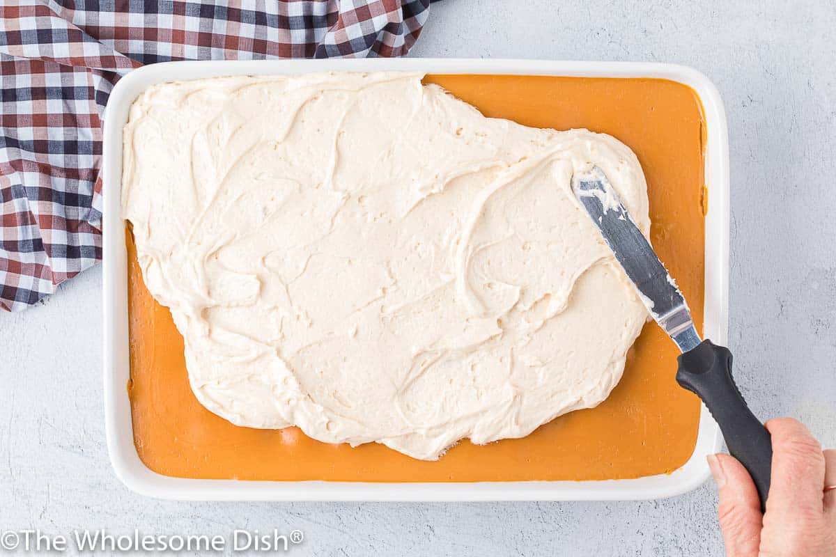 Spreading frosting on a pumpkin cake.