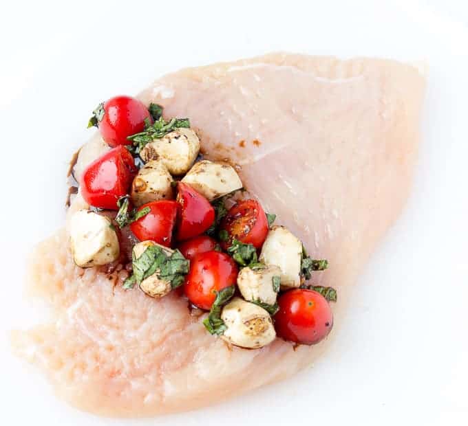 Caprese mixture on a thin raw chicken breast