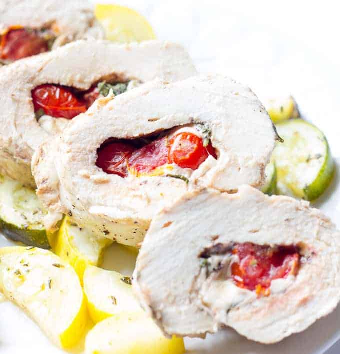 sliced Caprese Stuffed Chicken and sliced squash on a white plate