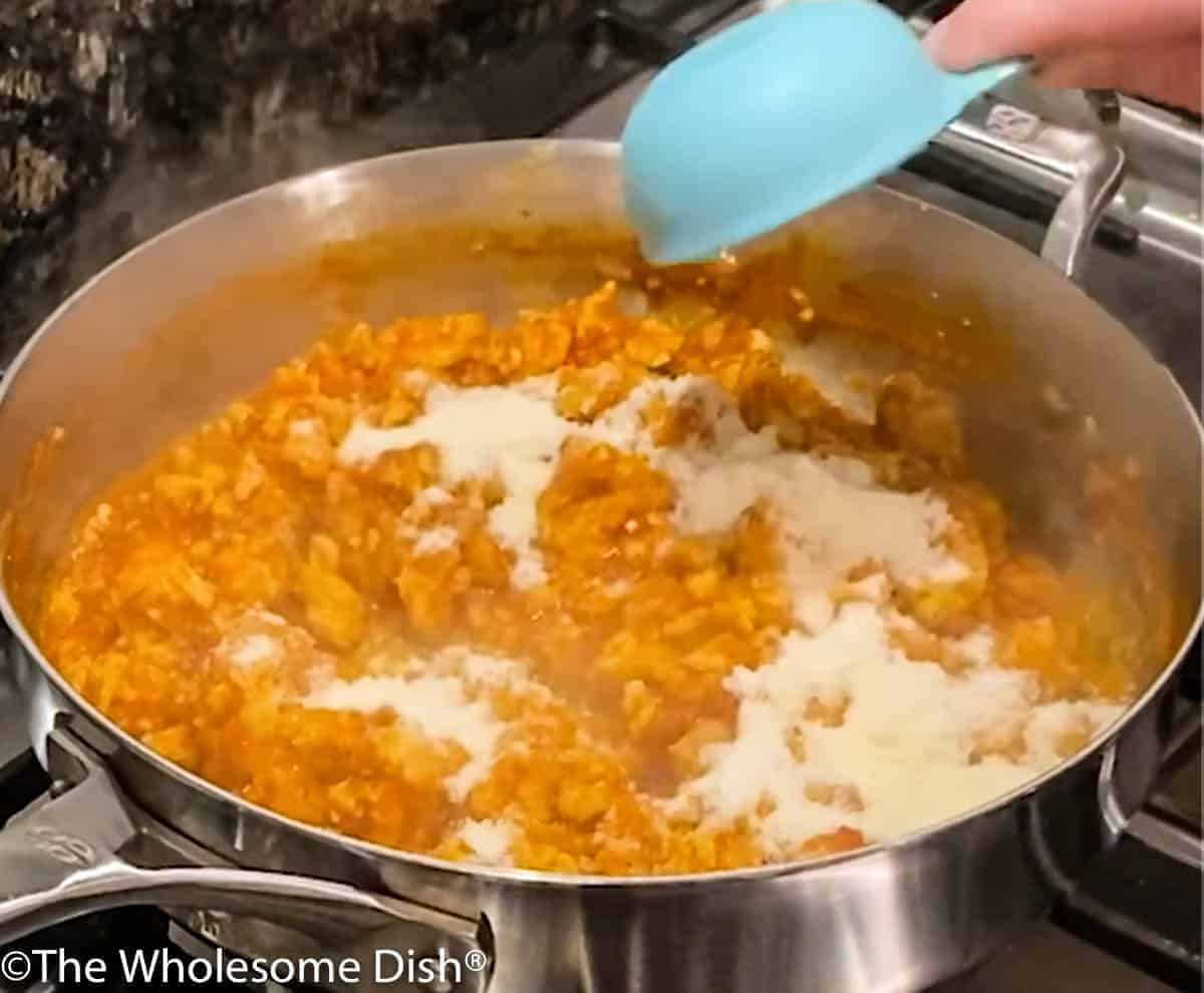 Adding grated parmesan cheese to ground chicken.