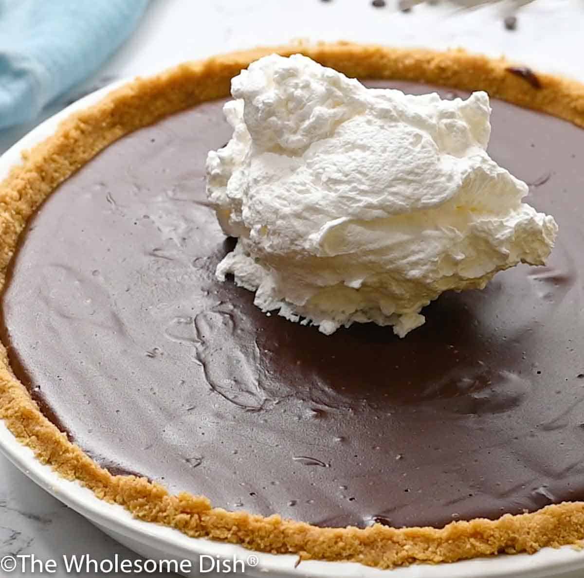 a dollop of whipped cream on top of a cold chocolate cream pie