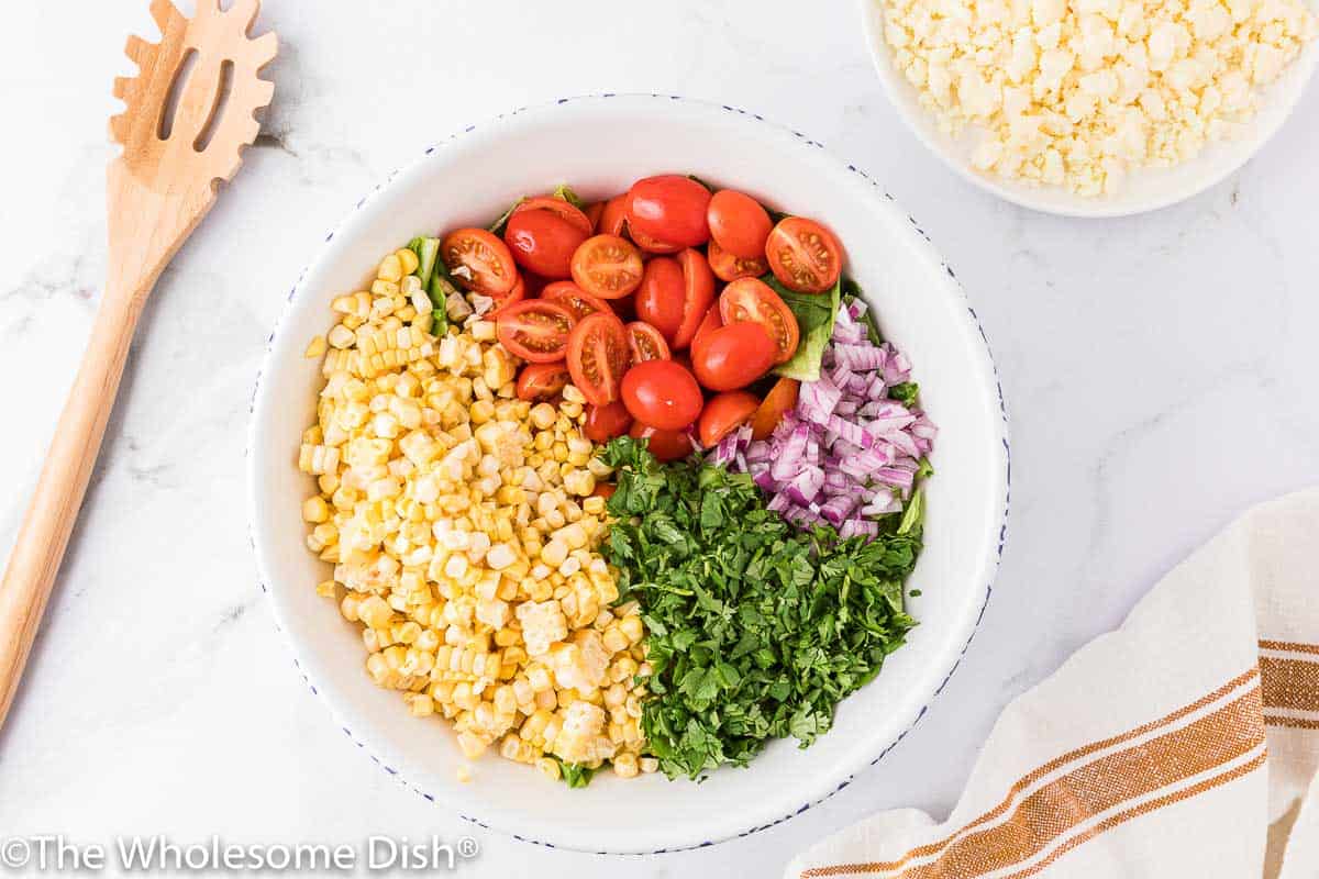 bowl full of fresh corn, tomatoes, onions, cilantro, and lettuce.