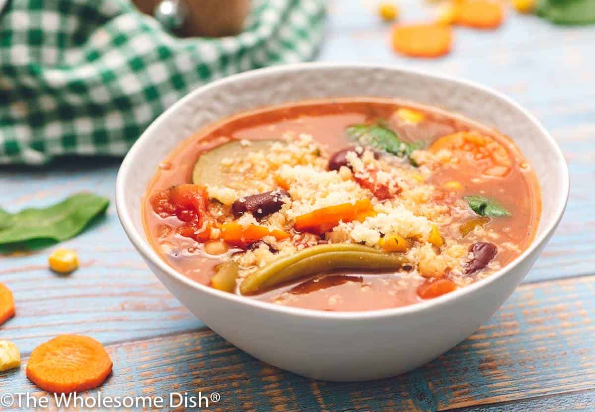 White bowl full of slow cooker minestrone soup topped with parmesan.