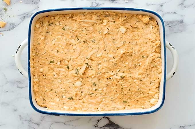 baking dish of chicken, mozzarella, cream cheese, buffalo sauce, and ranch dressing ready to be baked for a dip