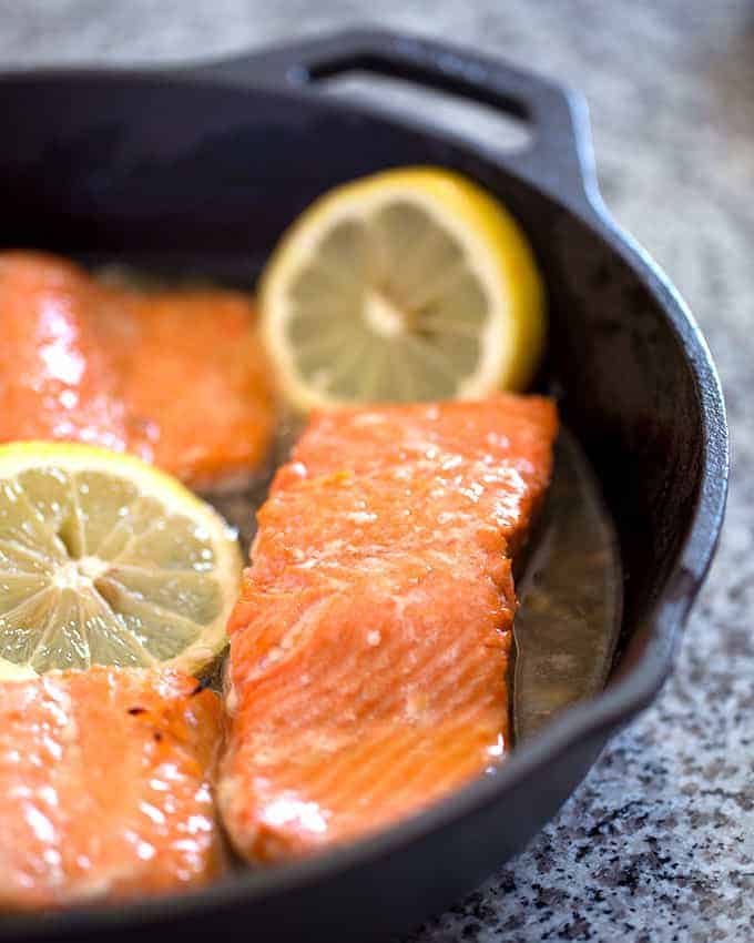 Cooked salmon in a cast iron skillet with lemon slices