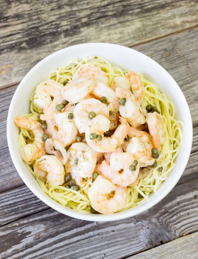 Shrimp Piccata over pasta in a white bowl