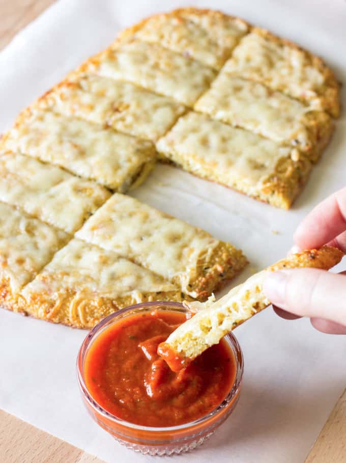 dipping Quinoa Crust garlic bread into a bowl of marinara sauce