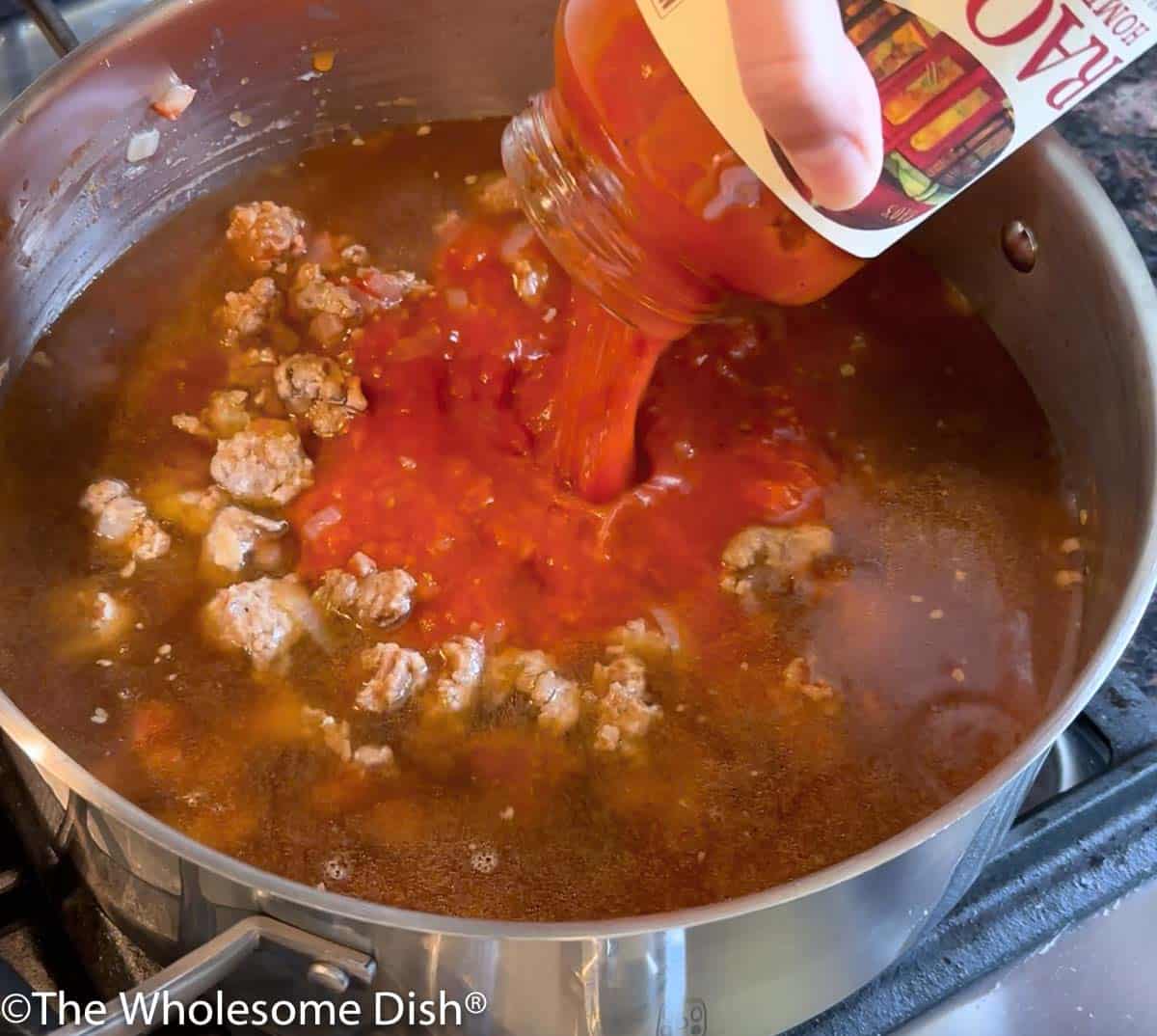 Beef broth and pasta sauce being added to the pot.