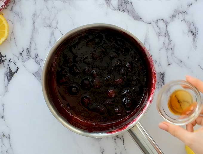 Pot of warm blueberry syrup with vanilla extract about to be added in.