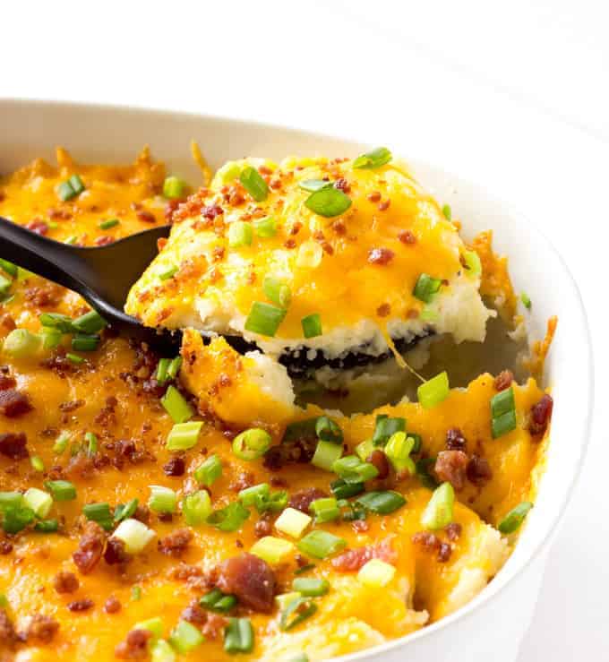 spoon scooping out cheesy mashed potato casserole