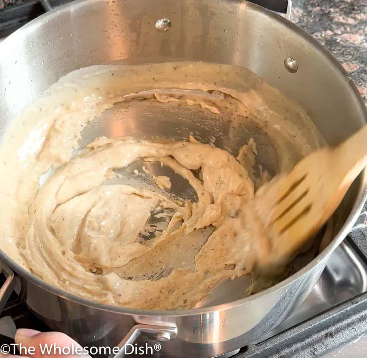 Liquid added to a roux in a pot.