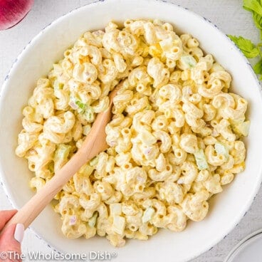 Large white serving bowl full of macaroni salad.