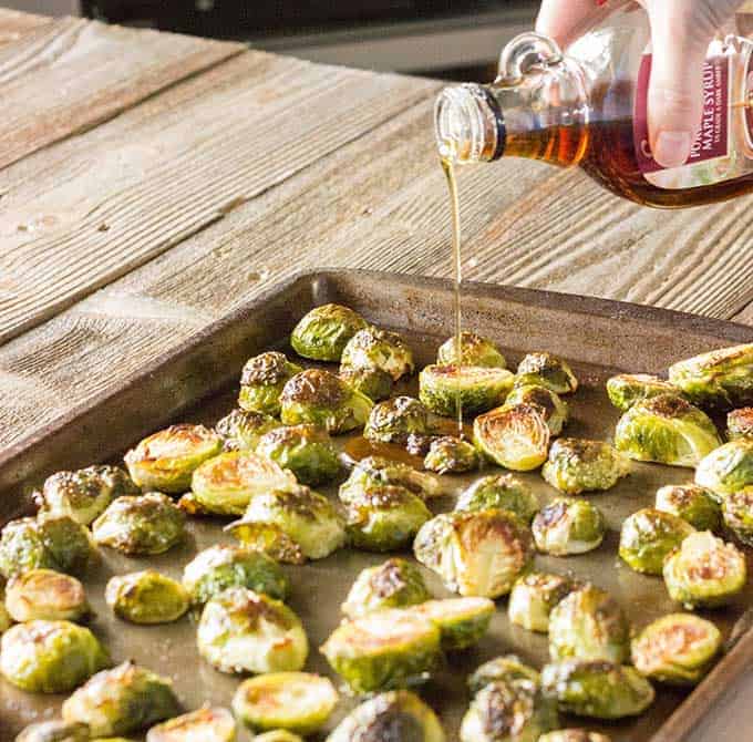 Maple syrup being poured over roasted brussels sprouts