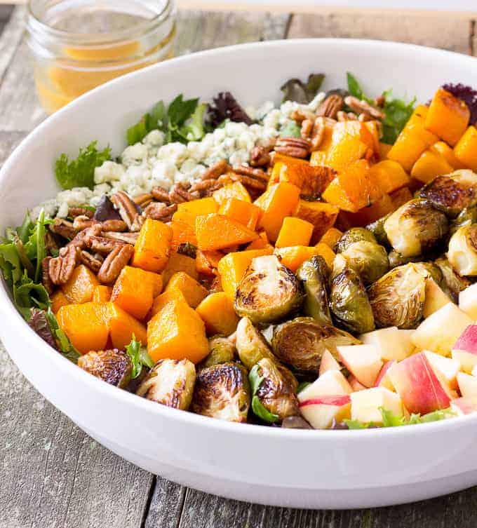 white bowl full of Roasted Butternut Squash & Brussels Sprouts Harvest Salad with Maple Cider Vinaigrette