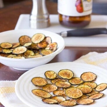 white bowl and plate full of Salt and Vinegar Zucchini Chips