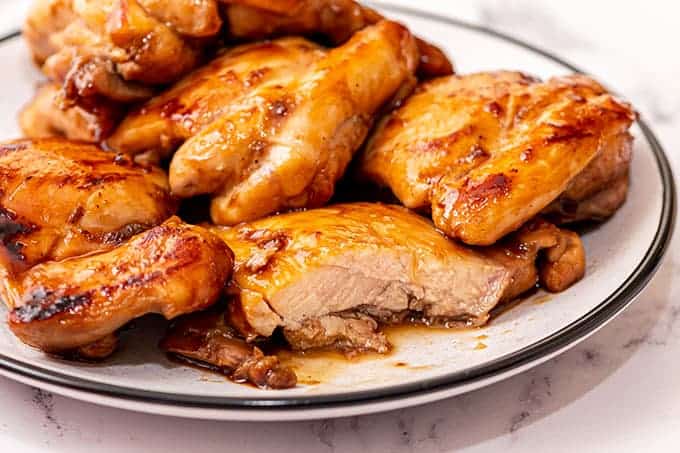 plate full of cooked chicken thighs coated in teriyaki glaze