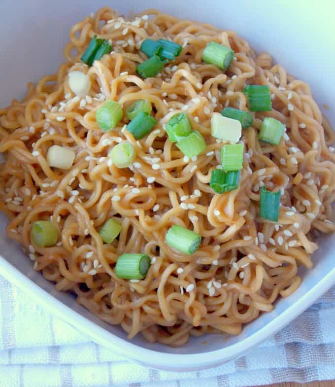 white bowl full of Sesame Peanut Butter Noodles topped with green onions