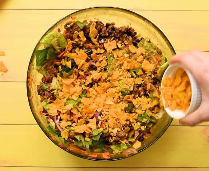 Adding crushed tortilla chips to the best taco salad