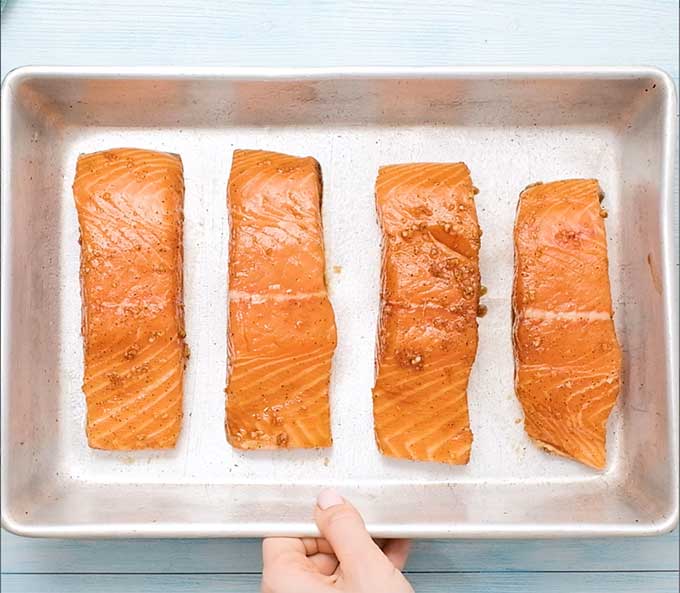 4 uncooked marinaded salmon fillets in a baking dish