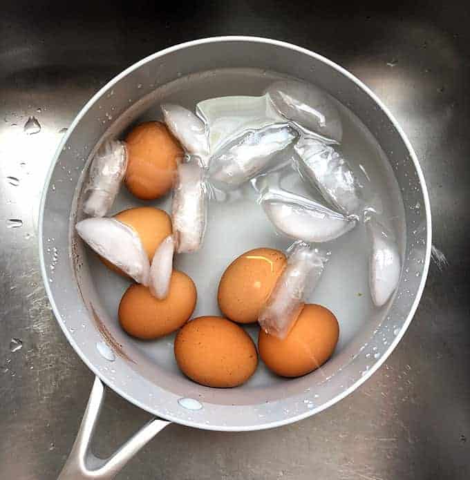 Cooked eggs cooling in a pot of ice water