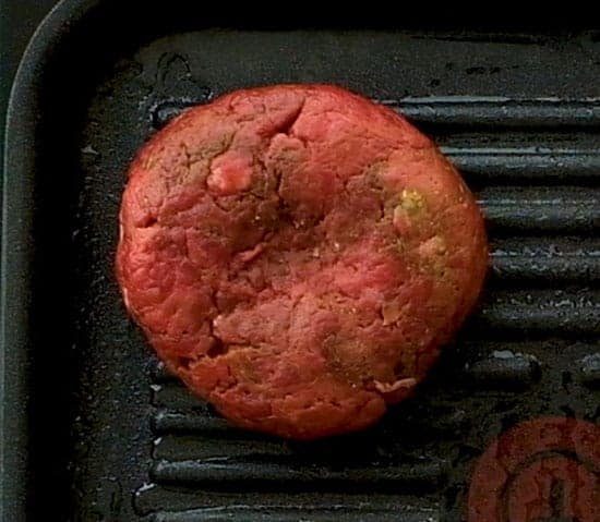 Burger patty cooking on a grill plate