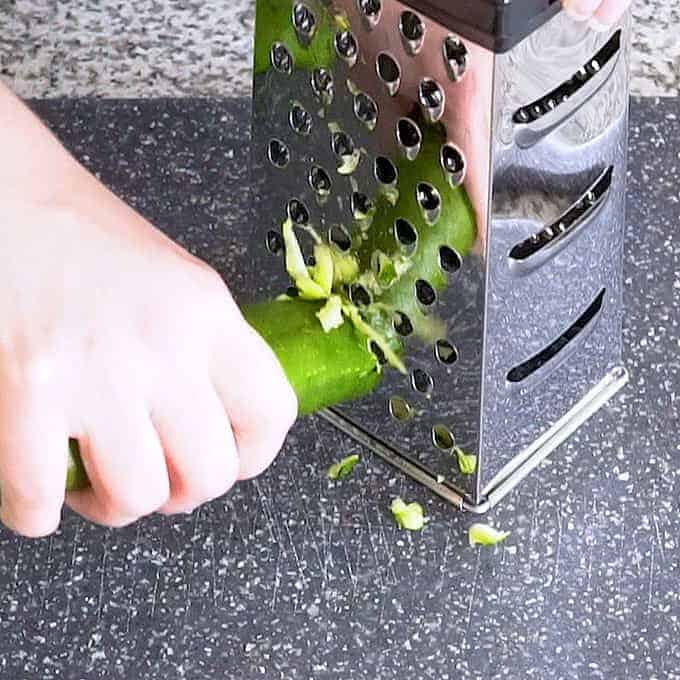 Grating zucchini on a box grater for zucchini bread