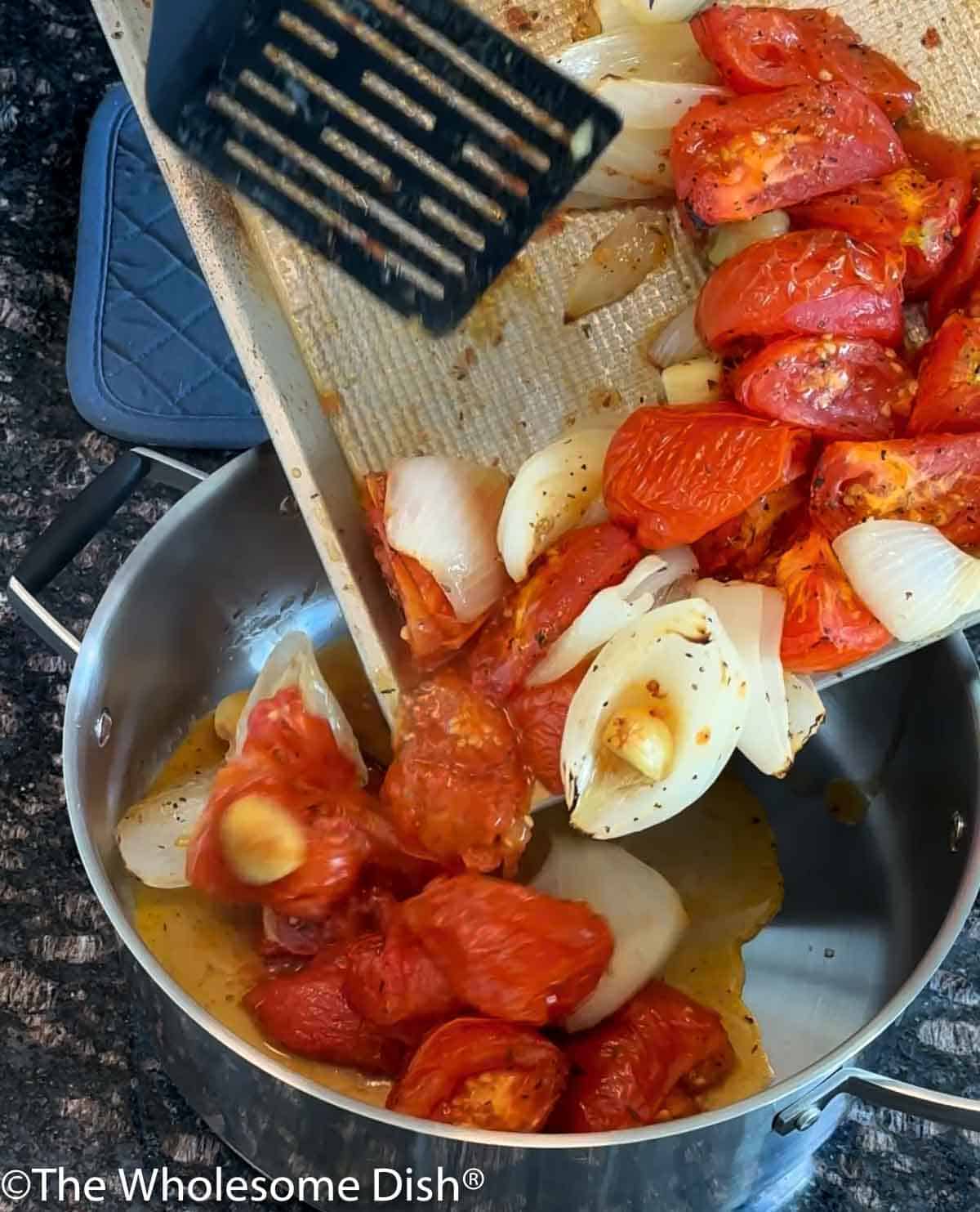 Transferring roasted vegetables to a soup pot.