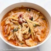 Bowl full of Tuscan chicken soup with parmesan cheese on top.