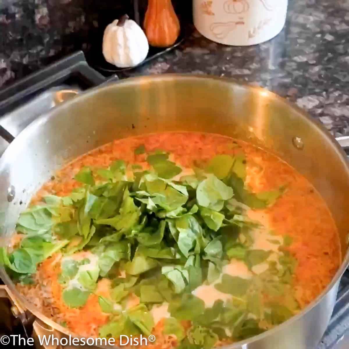 Adding pulled rotisserie chicken meat and chopped spinach to the pot.