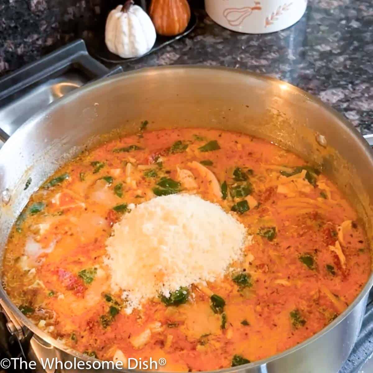 Adding grated parmesan cheese to the pot.